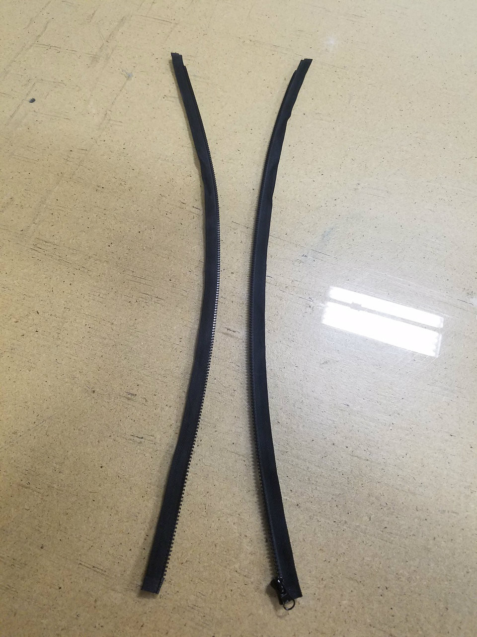 Two unzipped side of the black 22 inch separating zipper laid out flat next to each other.