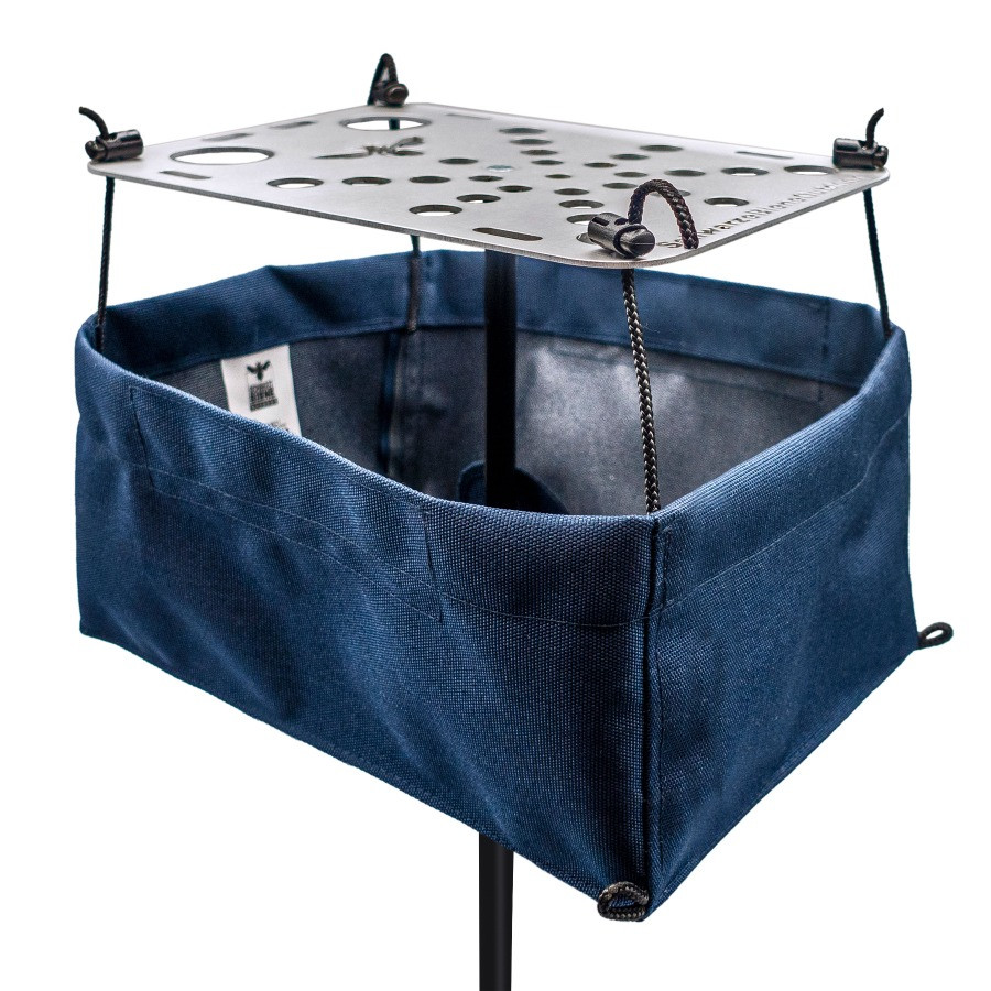 A navy blue Schwarze Biene camping table storage bag attached and hanging beneath a metal camping table.